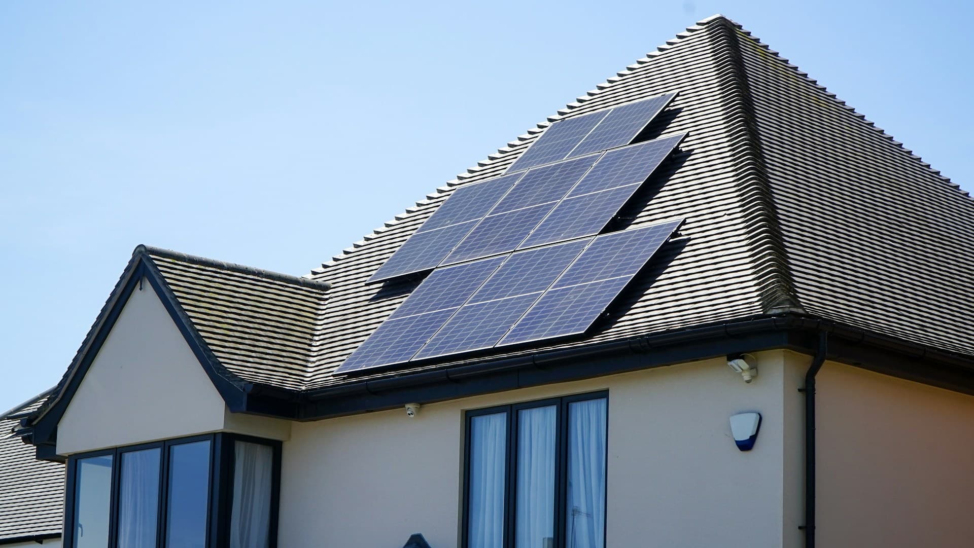 A modern architectural house with black solar panels integrated into a sleek metallic roof.